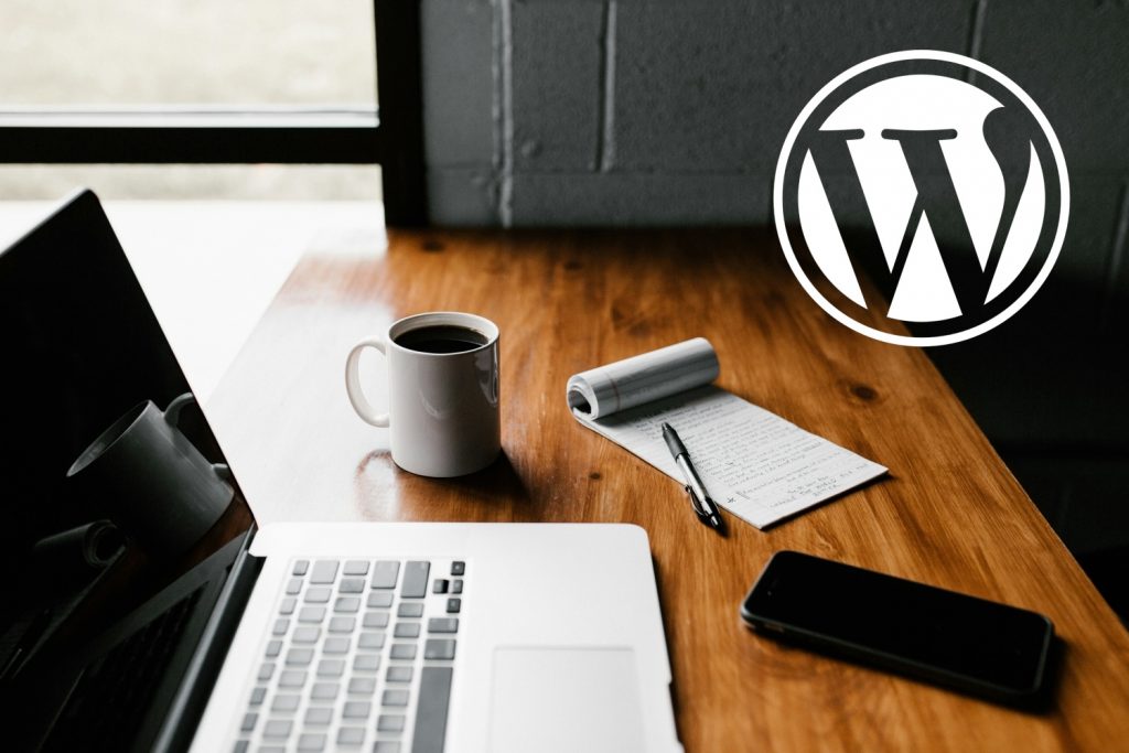 bureau avec ordinateur et carnet plus logo wordpress